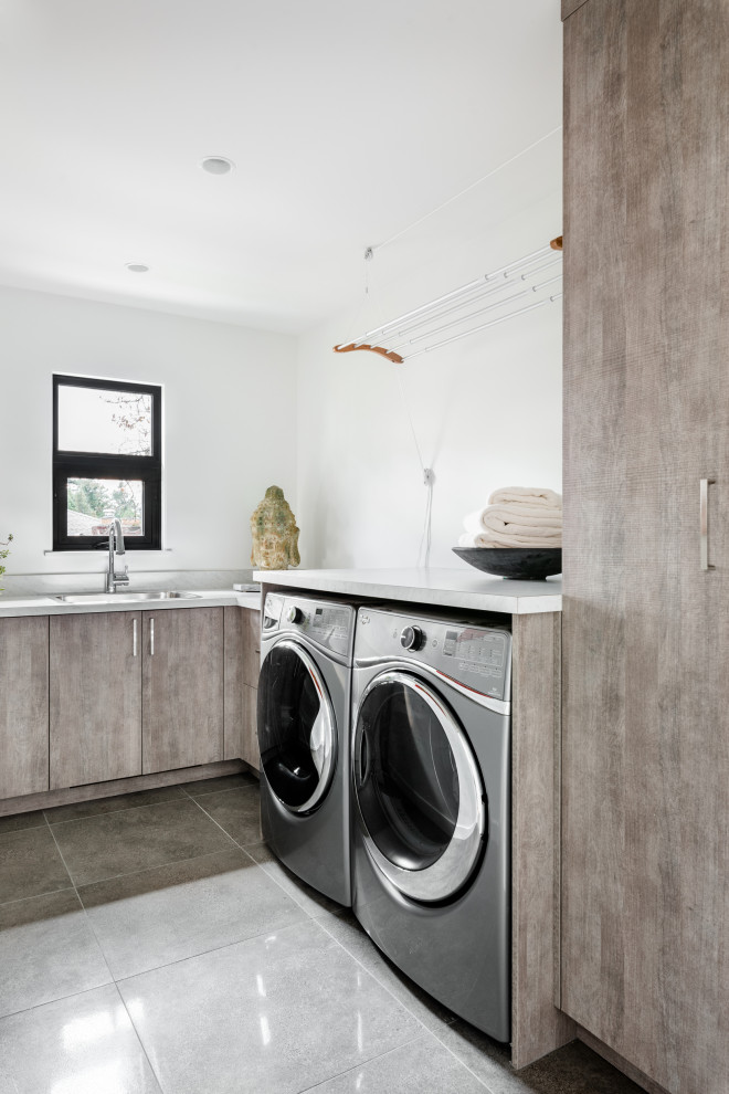 Esempio di una sala lavanderia bohémian con lavello a vasca singola, ante lisce, ante marroni, pareti bianche, lavatrice e asciugatrice affiancate, pavimento grigio e top bianco