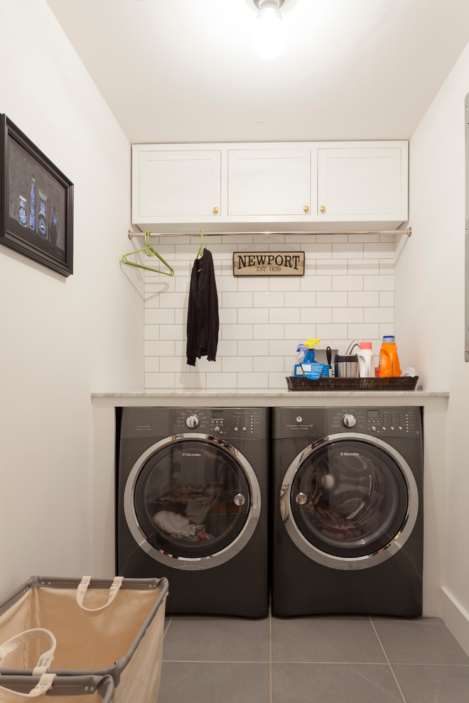 Exempel på en liten linjär tvättstuga enbart för tvätt, med skåp i shakerstil, vita skåp, vita väggar, klinkergolv i porslin, en tvättmaskin och torktumlare bredvid varandra och granitbänkskiva