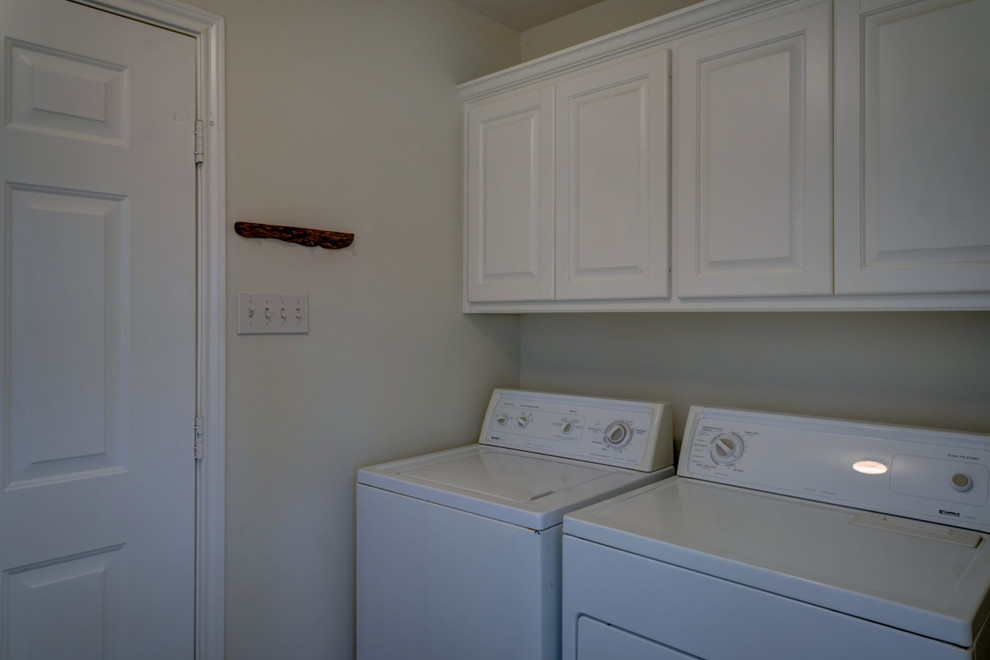Idee per una piccola sala lavanderia tradizionale con ante con bugna sagomata, ante bianche, pareti beige e lavatrice e asciugatrice affiancate