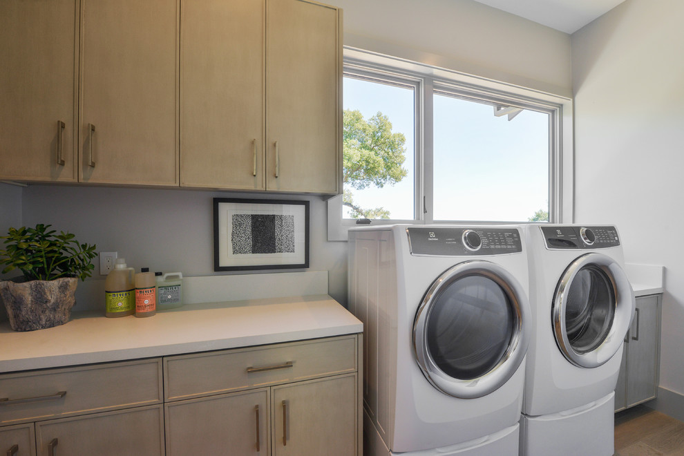 Ispirazione per una sala lavanderia minimal con ante in legno chiaro, pareti grigie, parquet chiaro, lavatrice e asciugatrice affiancate e top bianco