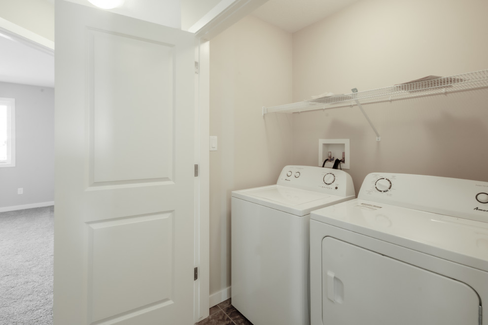Foto di un piccolo ripostiglio-lavanderia tradizionale con pareti beige, pavimento in linoleum e lavatrice e asciugatrice affiancate