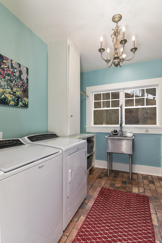Immagine di una sala lavanderia country di medie dimensioni con ante lisce, ante bianche, pareti blu, pavimento in mattoni e lavatrice e asciugatrice affiancate
