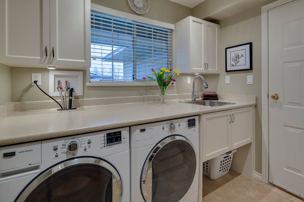 Large elegant single-wall porcelain tile dedicated laundry room photo in Vancouver with a drop-in sink, shaker cabinets, white cabinets, a side-by-side washer/dryer and beige walls