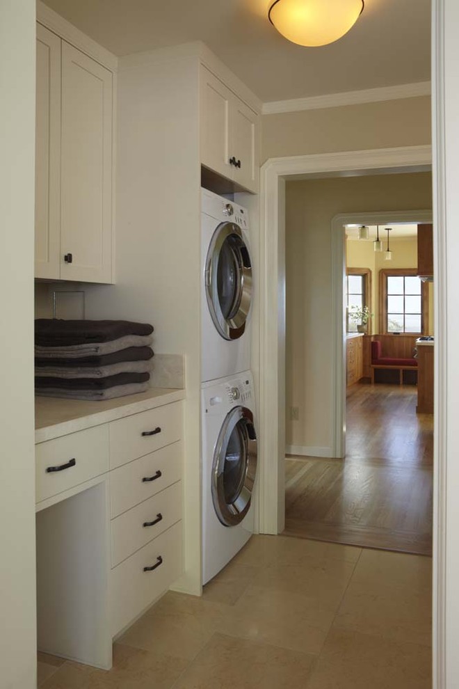 Immagine di una lavanderia tradizionale con lavatrice e asciugatrice a colonna, pavimento beige e top beige