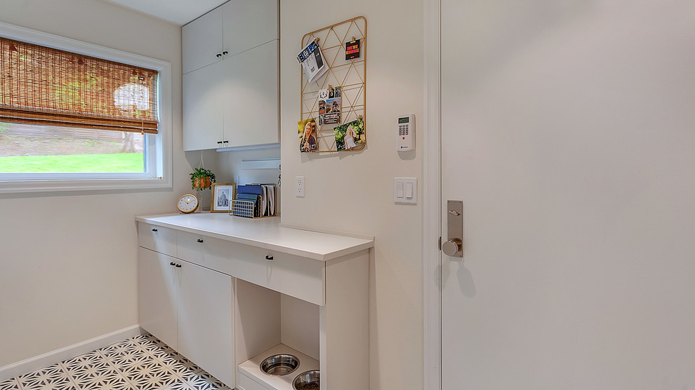 Example of a small mid-century modern galley ceramic tile and blue floor dedicated laundry room design in Portland with flat-panel cabinets, gray cabinets, quartz countertops, gray walls, a stacked washer/dryer and gray countertops