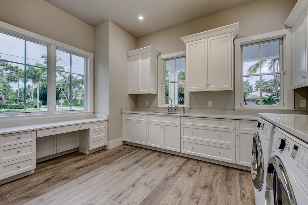 Inspiration for a large transitional u-shaped light wood floor utility room remodel in Other with recessed-panel cabinets, white cabinets, quartz countertops, gray walls and a side-by-side washer/dryer