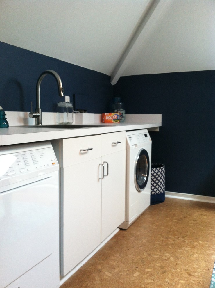 Immagine di una lavanderia multiuso tradizionale di medie dimensioni con lavello a vasca singola, ante bianche, top in laminato, pareti blu, pavimento in sughero e lavatrice e asciugatrice affiancate