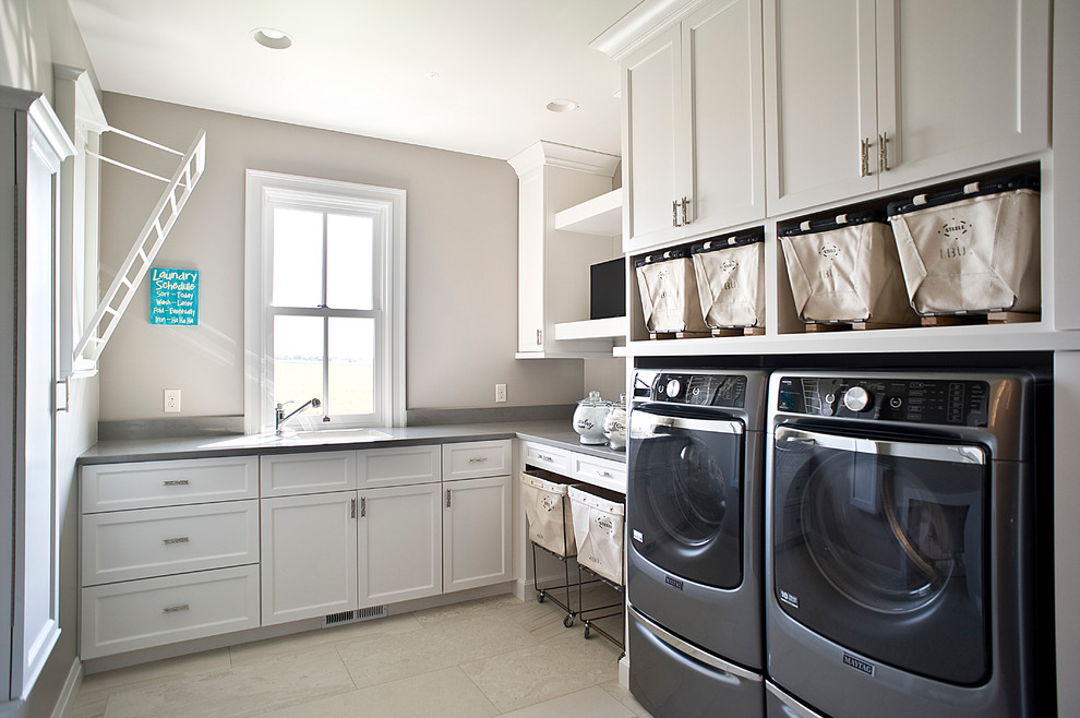 Große Klassische Waschküche in L-Form mit Unterbauwaschbecken, Schrankfronten im Shaker-Stil, weißen Schränken, beiger Wandfarbe, Keramikboden und Waschmaschine und Trockner nebeneinander in Sonstige