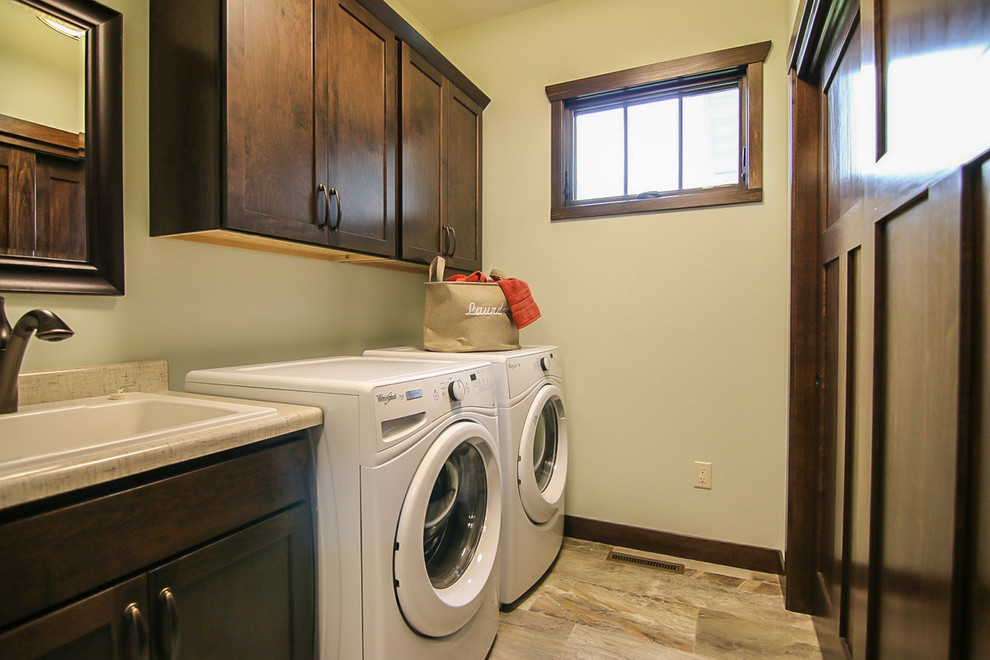 Photo of a traditional single-wall separated utility room in Milwaukee with a built-in sink, shaker cabinets, dark wood cabinets, laminate countertops, grey walls, vinyl flooring and a side by side washer and dryer.