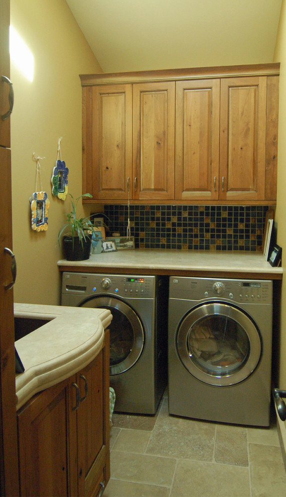 Immagine di una sala lavanderia chic di medie dimensioni con lavello sottopiano, ante con bugna sagomata, top in pietra calcarea, pavimento in travertino, lavatrice e asciugatrice affiancate, ante in legno scuro e pareti beige