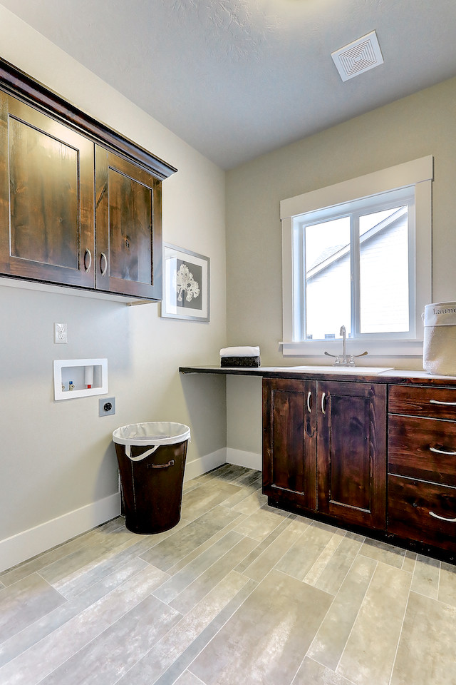 Exempel på en mellanstor klassisk tvättstuga enbart för tvätt, med en enkel diskho, släta luckor, skåp i mellenmörkt trä, laminatbänkskiva, beige väggar, linoleumgolv och en tvättmaskin och torktumlare bredvid varandra