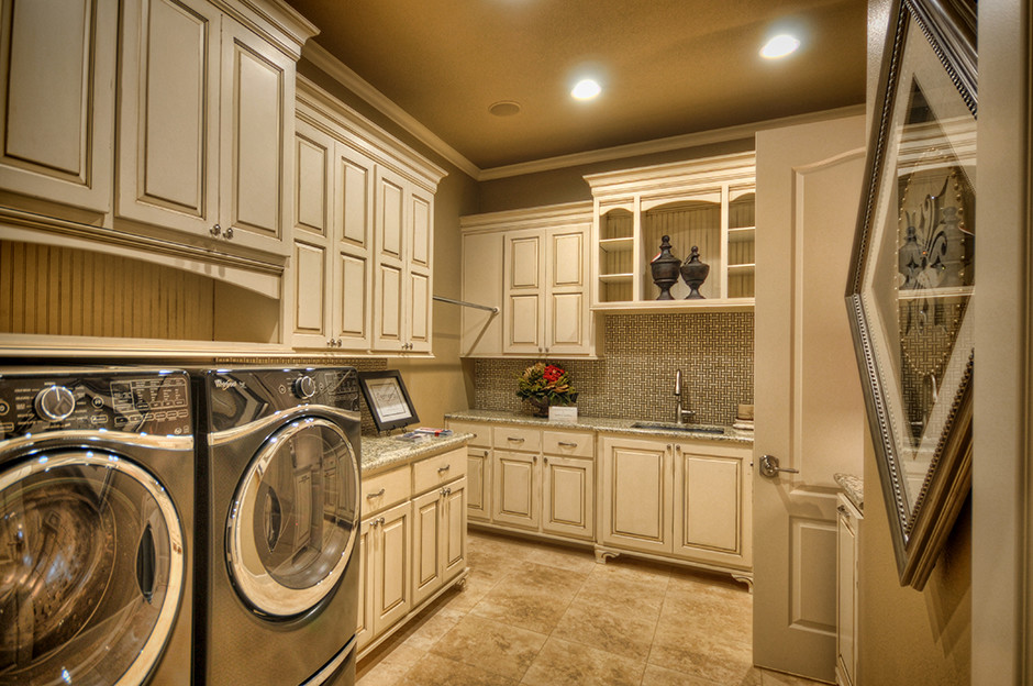 This is an example of a large classic single-wall laundry cupboard with a submerged sink, raised-panel cabinets, beige cabinets, granite worktops, beige walls, porcelain flooring, a side by side washer and dryer and brown floors.