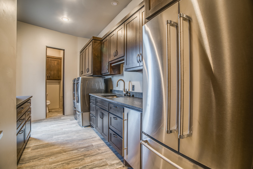 Large traditional galley utility room in Austin with a submerged sink, shaker cabinets, dark wood cabinets, granite worktops, porcelain flooring, a side by side washer and dryer and grey walls.