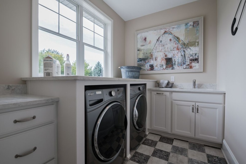 Mittelgroße Klassische Waschküche in L-Form mit Unterbauwaschbecken, Schrankfronten mit vertiefter Füllung, weißen Schränken, Marmor-Arbeitsplatte, weißer Wandfarbe, Keramikboden, Waschmaschine und Trockner nebeneinander und buntem Boden in Minneapolis