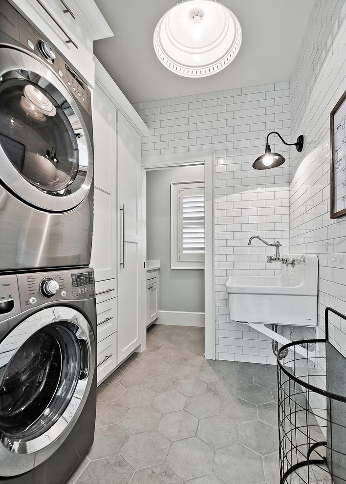 Foto på en lantlig linjär tvättstuga, med luckor med infälld panel, vita skåp, en tvättpelare och grått golv
