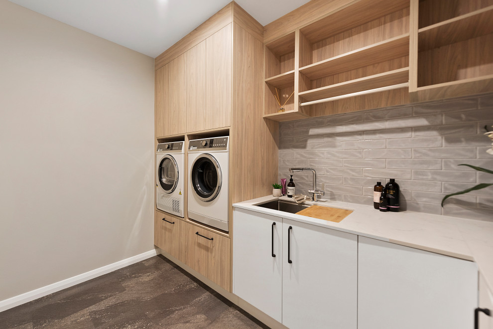 Ispirazione per una sala lavanderia minimalista di medie dimensioni con lavello sottopiano, top in superficie solida, pavimento in sughero e lavatrice e asciugatrice affiancate