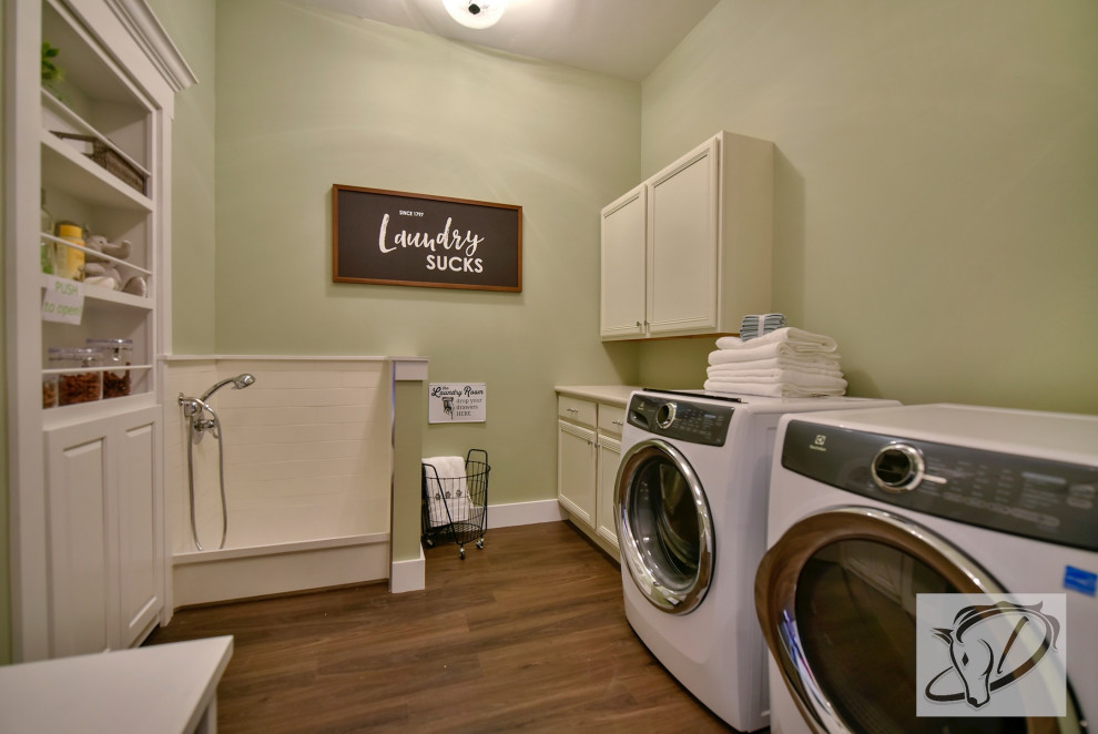 Immagine di una grande lavanderia multiuso tradizionale con pareti verdi, pavimento in vinile, lavatrice e asciugatrice affiancate, pavimento marrone e top bianco