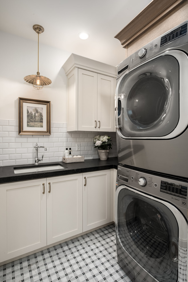 Farmhouse l-shaped multicolored floor dedicated laundry room photo in Salt Lake City with an undermount sink, shaker cabinets, white cabinets, white walls, a side-by-side washer/dryer and black countertops