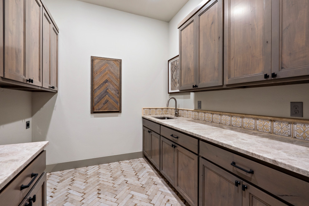 Example of a large cottage porcelain tile and multicolored floor dedicated laundry room design in Austin with an undermount sink, shaker cabinets, gray cabinets, marble countertops, beige backsplash, mosaic tile backsplash, gray walls, a side-by-side washer/dryer and beige countertops