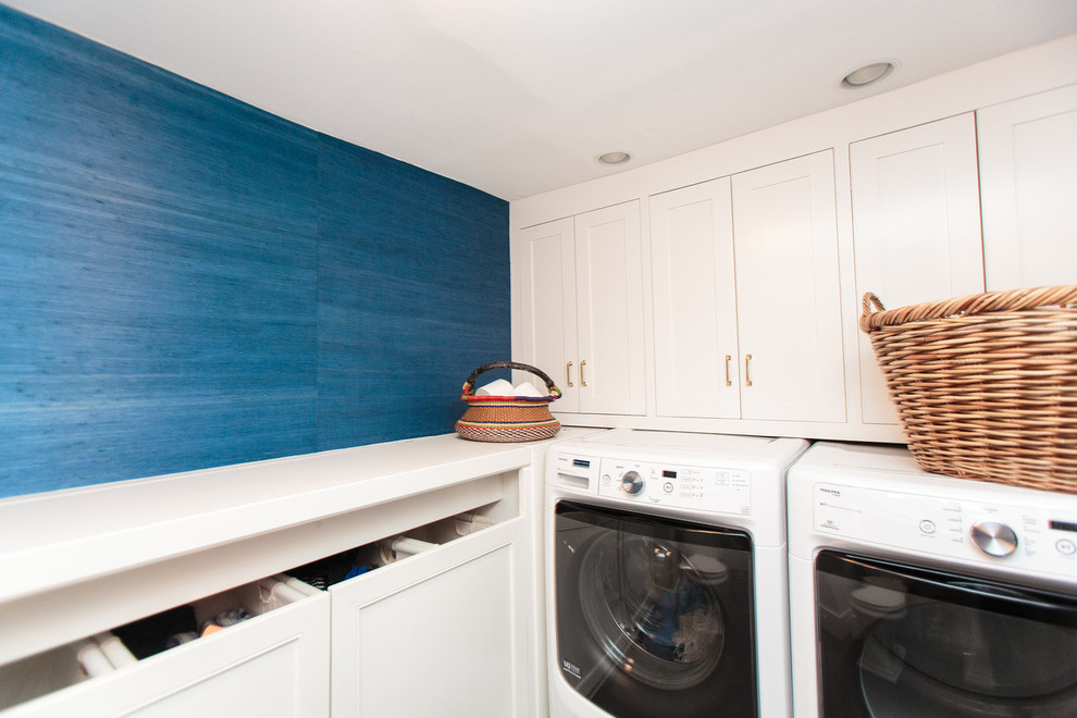 Imagen de lavadero multiusos clásico de tamaño medio con armarios con paneles empotrados, paredes azules y lavadora y secadora juntas