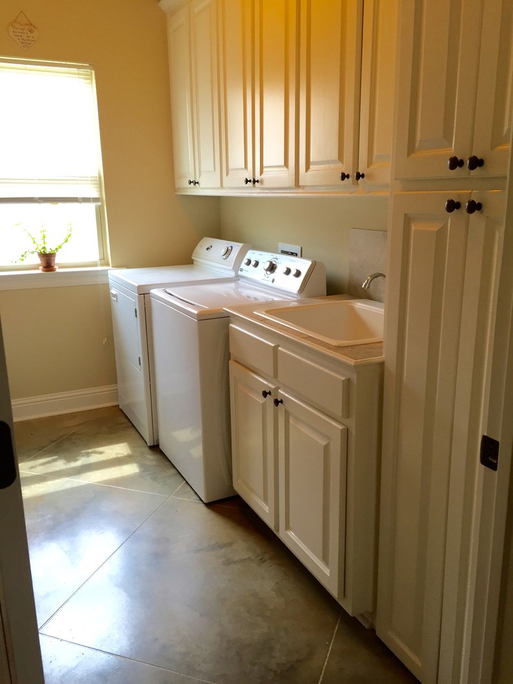 Idéer för stora vintage parallella tvättstugor enbart för tvätt, med en nedsänkt diskho, luckor med infälld panel, vita skåp, kaklad bänkskiva, beige väggar, betonggolv och en tvättmaskin och torktumlare bredvid varandra