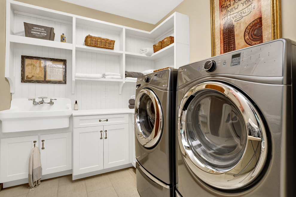 Immagine di una sala lavanderia chic con lavello stile country, ante in stile shaker, ante bianche, pareti beige, lavatrice e asciugatrice affiancate, pavimento beige e top bianco