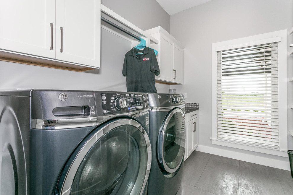 Dedicated laundry room - mid-sized modern galley ceramic tile and gray floor dedicated laundry room idea in Wichita with shaker cabinets, white cabinets, laminate countertops, gray walls, a side-by-side washer/dryer and gray countertops