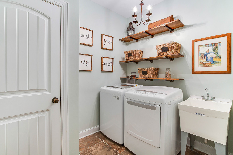 Foto på en vintage linjär tvättstuga enbart för tvätt, med en allbänk, grå väggar, en tvättmaskin och torktumlare bredvid varandra och brunt golv