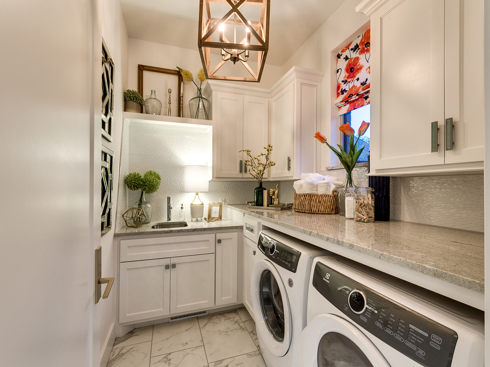 Klassische Waschküche in L-Form mit Unterbauwaschbecken, weißen Schränken, weißer Wandfarbe, Waschmaschine und Trockner nebeneinander und Schrankfronten mit vertiefter Füllung in Oklahoma City