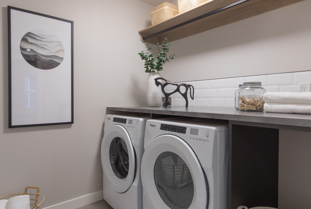 Einzeilige, Mittelgroße Moderne Waschküche mit Küchenrückwand in Weiß, Rückwand aus Metrofliesen, beiger Wandfarbe, Keramikboden, Waschmaschine und Trockner nebeneinander und grauem Boden in Calgary