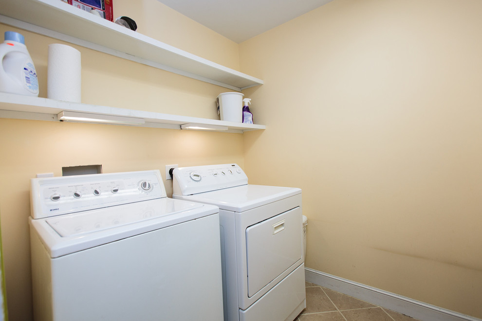 Immagine di una sala lavanderia tradizionale con pavimento con piastrelle in ceramica e lavatrice e asciugatrice affiancate