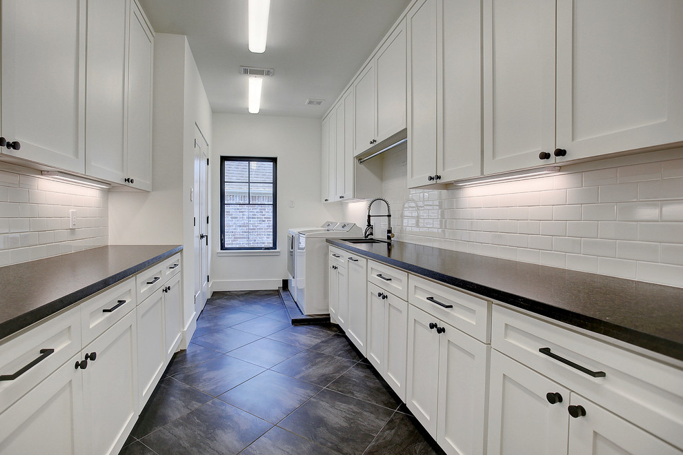 Inspiration for a large traditional galley utility room in Houston with a submerged sink, recessed-panel cabinets, white cabinets, granite worktops, white walls, porcelain flooring, a side by side washer and dryer, black floors and black worktops.
