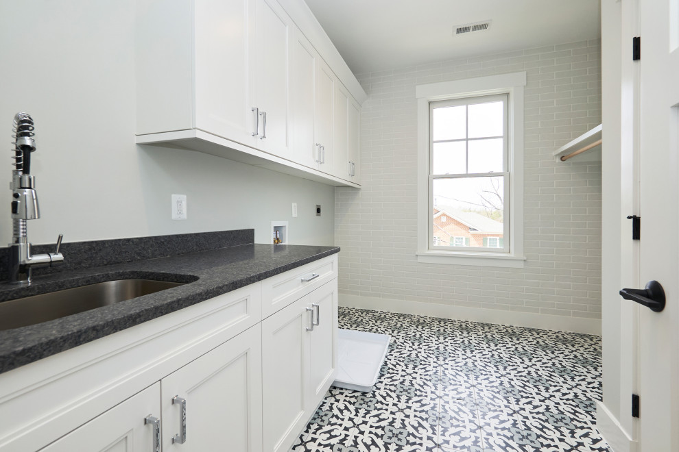 Example of a large transitional galley porcelain tile and multicolored floor dedicated laundry room design in DC Metro with an undermount sink, shaker cabinets, white cabinets, granite countertops, white walls, a side-by-side washer/dryer and black countertops
