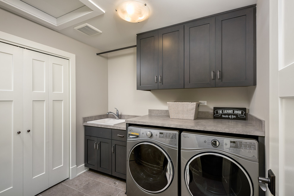 Dedicated laundry room - mid-sized contemporary galley ceramic tile and beige floor dedicated laundry room idea in Chicago with a drop-in sink, raised-panel cabinets, laminate countertops, gray walls, a side-by-side washer/dryer and dark wood cabinets