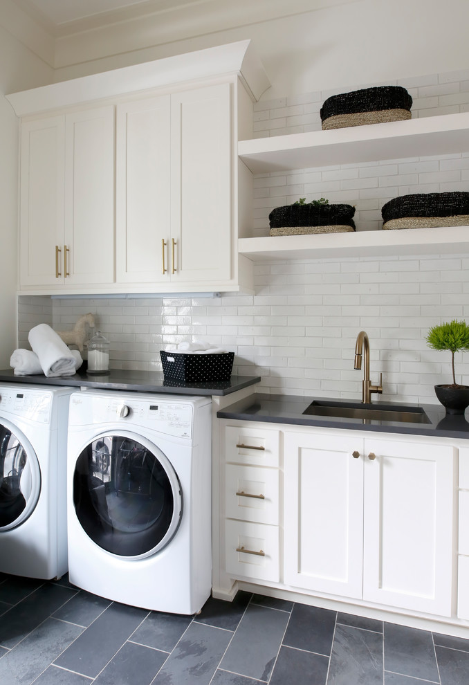 Idéer för maritima linjära svart tvättstugor enbart för tvätt, med en undermonterad diskho, skåp i shakerstil, vita skåp, vita väggar, en tvättmaskin och torktumlare bredvid varandra och grått golv