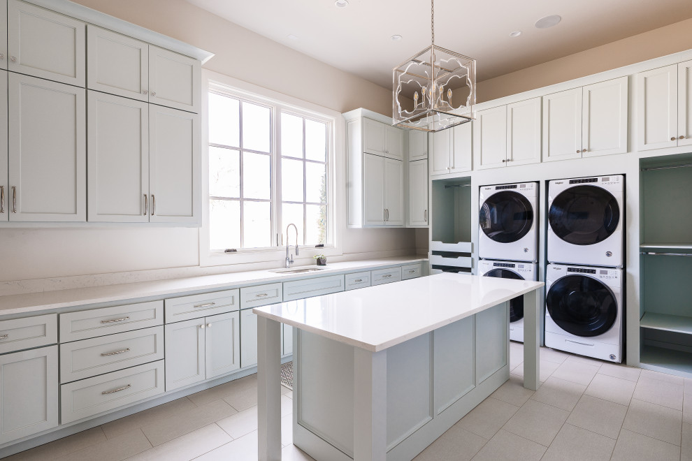Expansive traditional u-shaped utility room in Oklahoma City with recessed-panel cabinets, blue cabinets, engineered stone countertops, white walls, ceramic flooring, a stacked washer and dryer and white worktops.
