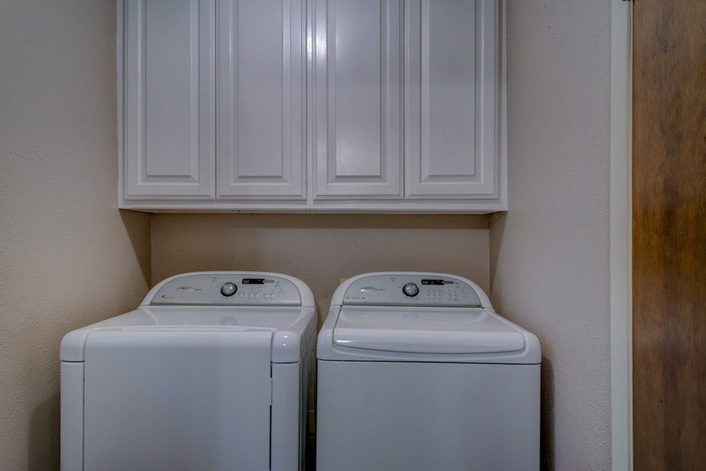 Esempio di una piccola sala lavanderia chic con ante con bugna sagomata, ante bianche, pareti beige e lavatrice e asciugatrice affiancate