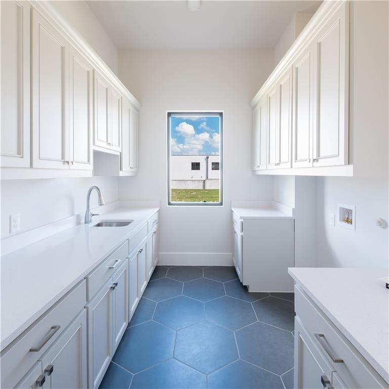 Immagine di una grande lavanderia multiuso minimalista con lavello sottopiano, ante bianche, pareti bianche, pavimento con piastrelle in ceramica, lavatrice e asciugatrice affiancate, pavimento nero e top bianco