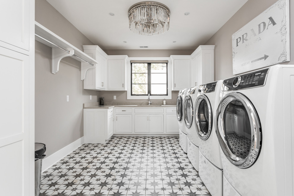 Immagine di una grande sala lavanderia mediterranea con ante bianche, pavimento in cemento, lavatrice e asciugatrice affiancate e pavimento multicolore