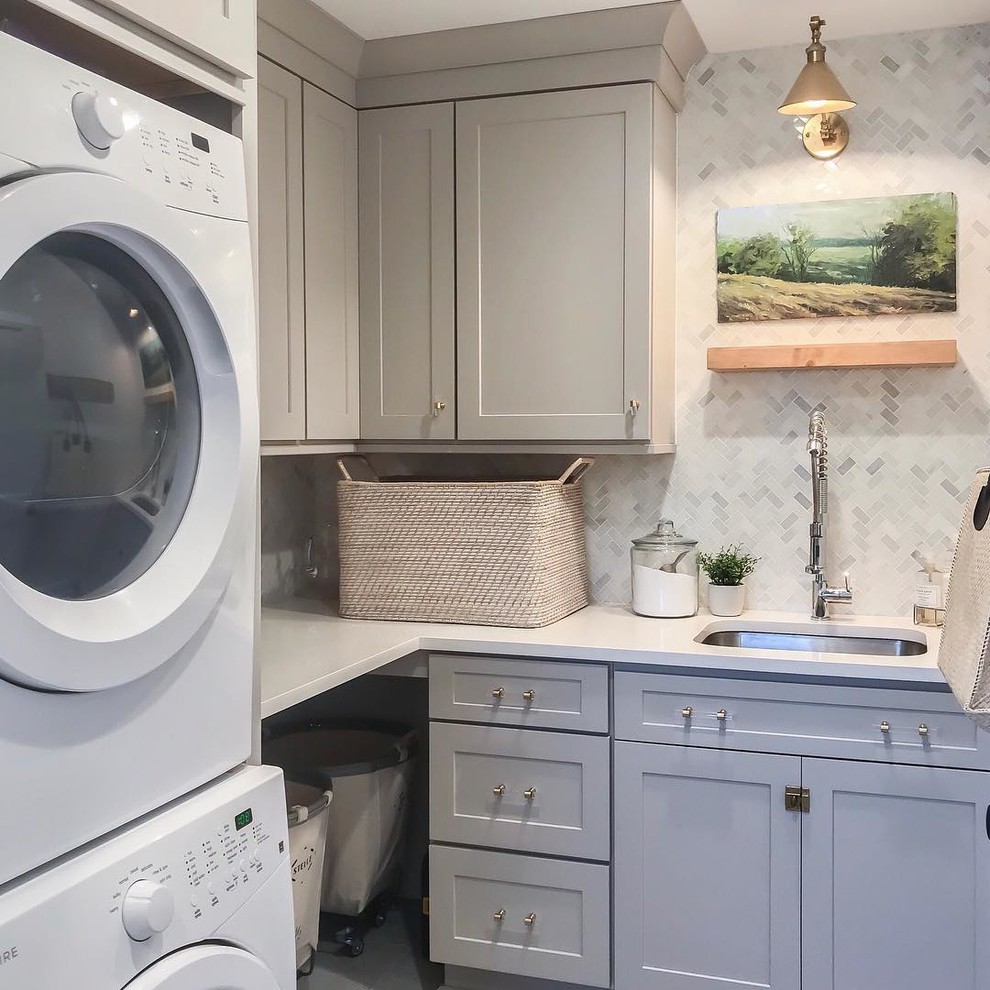 Design ideas for a traditional l-shaped separated utility room in New York with a submerged sink, shaker cabinets, grey cabinets, a stacked washer and dryer and white worktops.