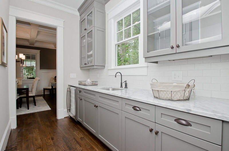 Immagine di una lavanderia stile americano di medie dimensioni con lavello a vasca singola, ante di vetro, ante grigie, top in marmo, pareti grigie e pavimento in legno massello medio