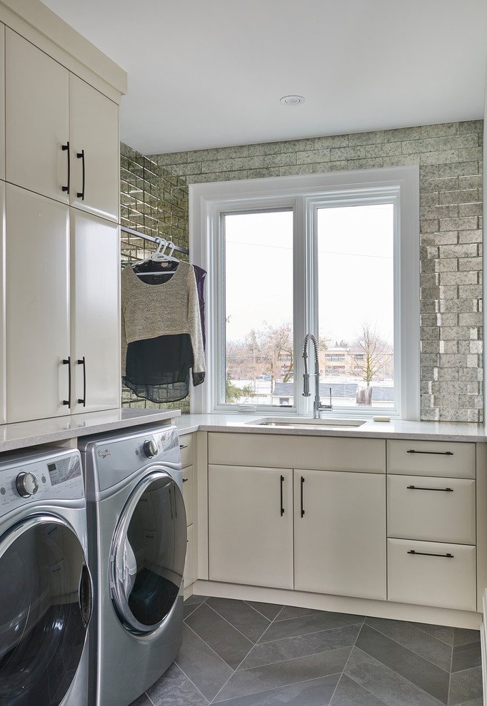 Esempio di una sala lavanderia minimal di medie dimensioni con lavello sottopiano, ante lisce, ante bianche, top in superficie solida, pareti grigie e lavatrice e asciugatrice affiancate