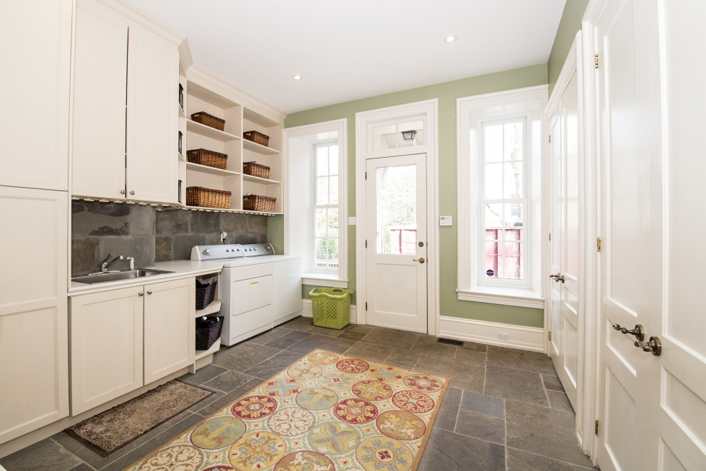 Photo of a large classic single-wall utility room in Philadelphia with a built-in sink, shaker cabinets, white cabinets, grey splashback, green walls, a side by side washer and dryer, grey floors and white worktops.