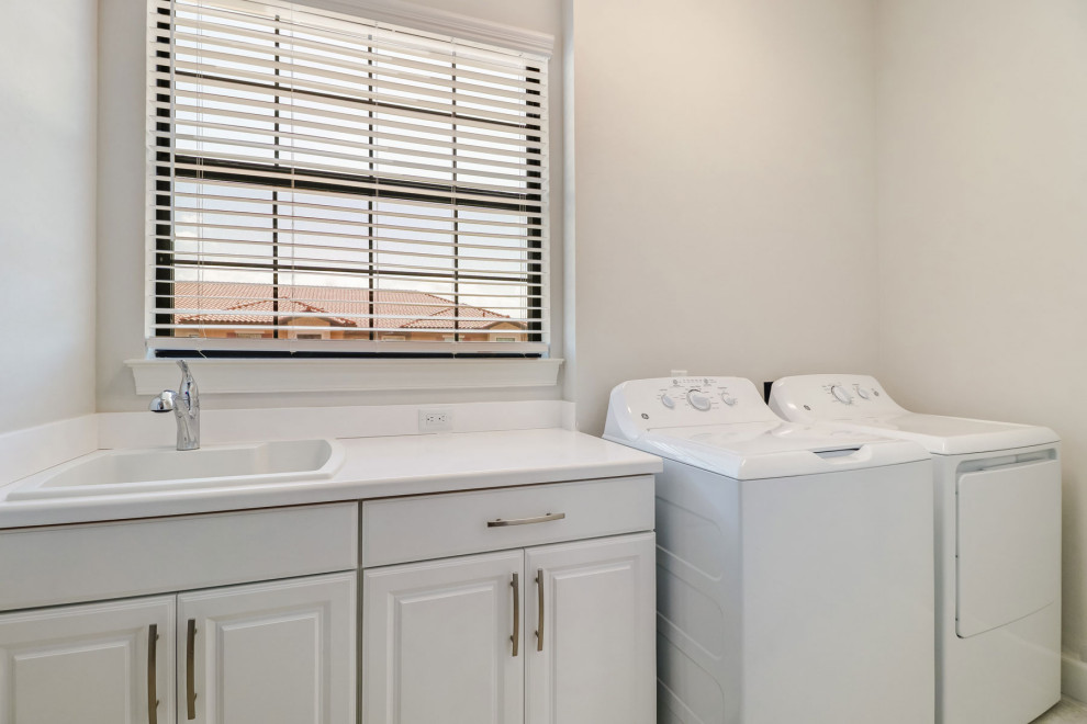 Example of a small 1950s galley ceramic tile and white floor dedicated laundry room design in Other with a drop-in sink, flat-panel cabinets, white cabinets, granite countertops, gray walls, a side-by-side washer/dryer and white countertops