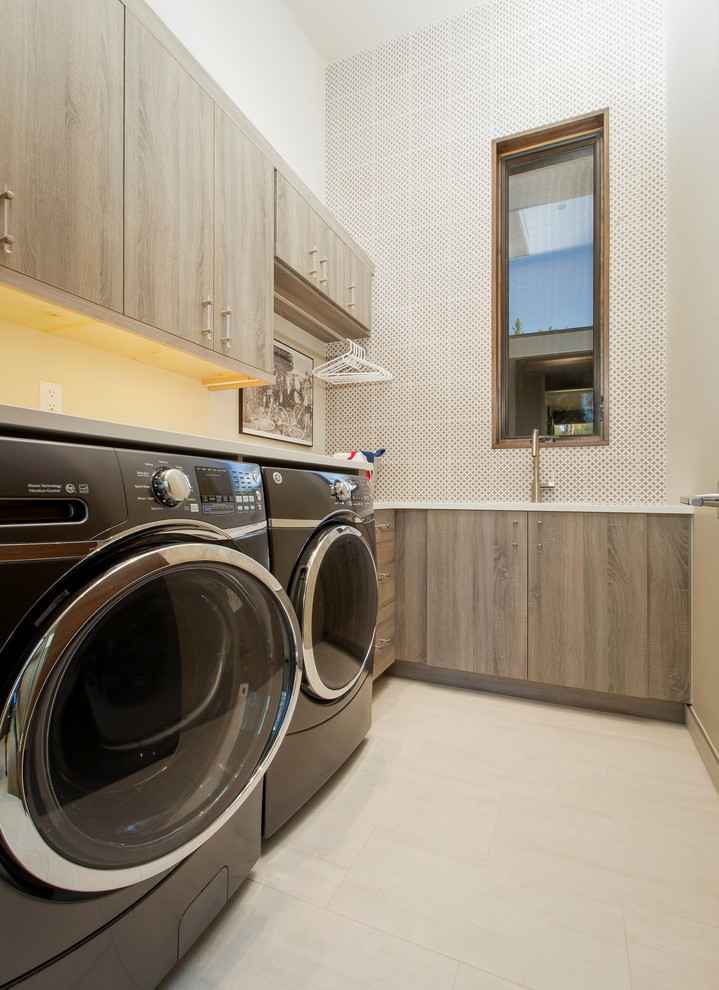 Ispirazione per una grande sala lavanderia design con ante lisce e lavatrice e asciugatrice affiancate