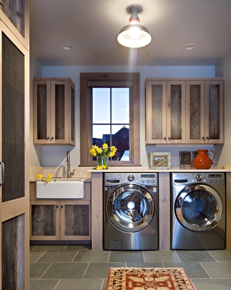 Diseño de cuarto de lavado lineal rústico con fregadero sobremueble, puertas de armario de madera oscura, paredes grises, lavadora y secadora juntas, suelo gris, encimeras beige y armarios estilo shaker