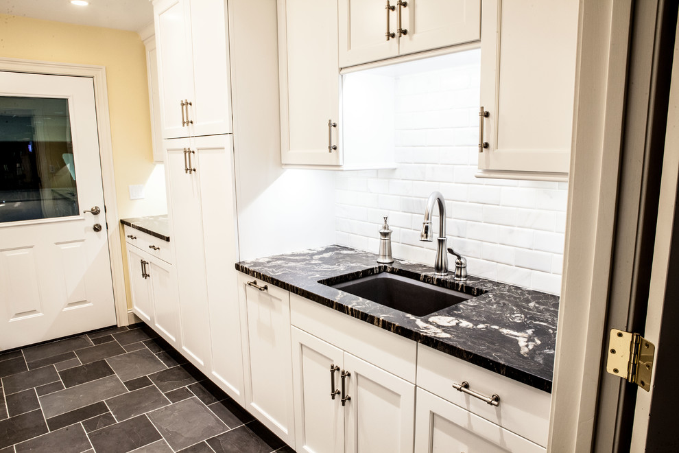 Photo of a medium sized classic galley separated utility room in Wichita with a submerged sink, recessed-panel cabinets, white cabinets, marble worktops, yellow walls, slate flooring, a side by side washer and dryer and grey floors.