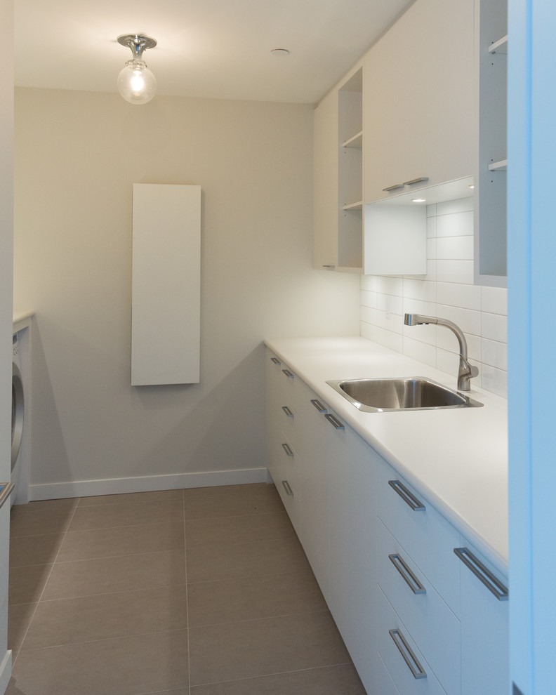 Design ideas for a modern galley utility room in Vancouver with a single-bowl sink, flat-panel cabinets and a side by side washer and dryer.