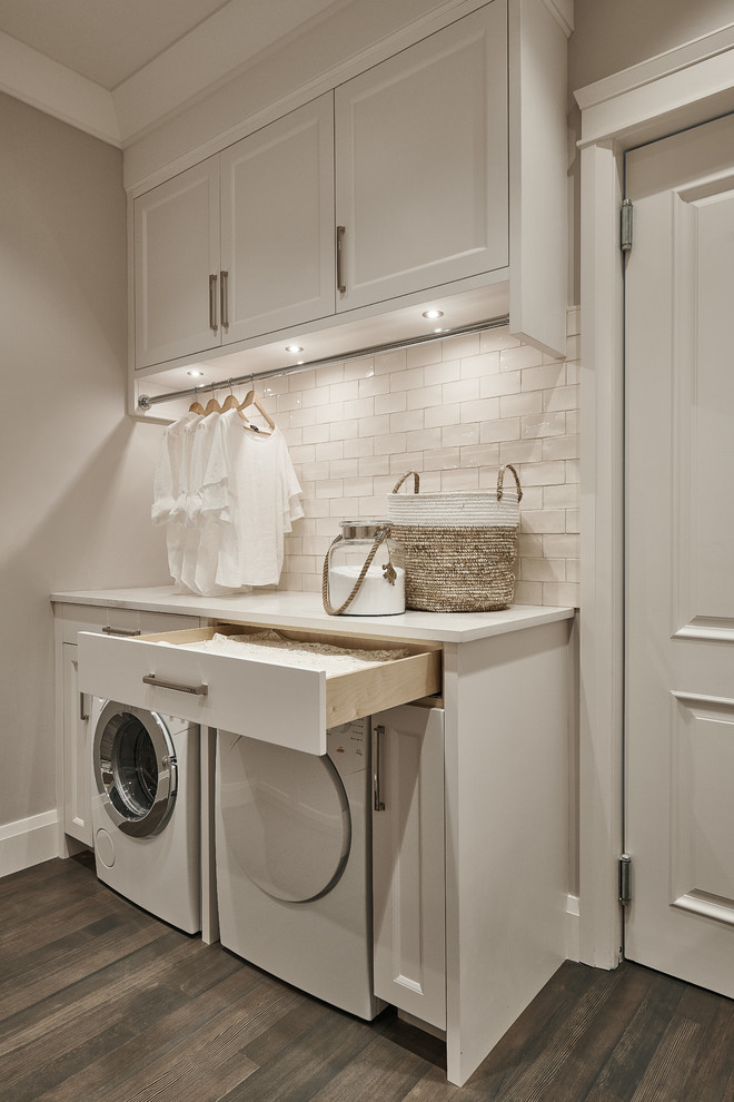 Design ideas for a large classic l-shaped utility room in Vancouver with a submerged sink, shaker cabinets, white cabinets, engineered stone countertops, white walls, dark hardwood flooring, a side by side washer and dryer, brown floors and white worktops.