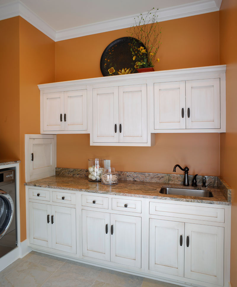 Inredning av ett klassiskt u-format grovkök, med en undermonterad diskho, skåp i shakerstil, vita skåp, orange väggar och en tvättmaskin och torktumlare bredvid varandra